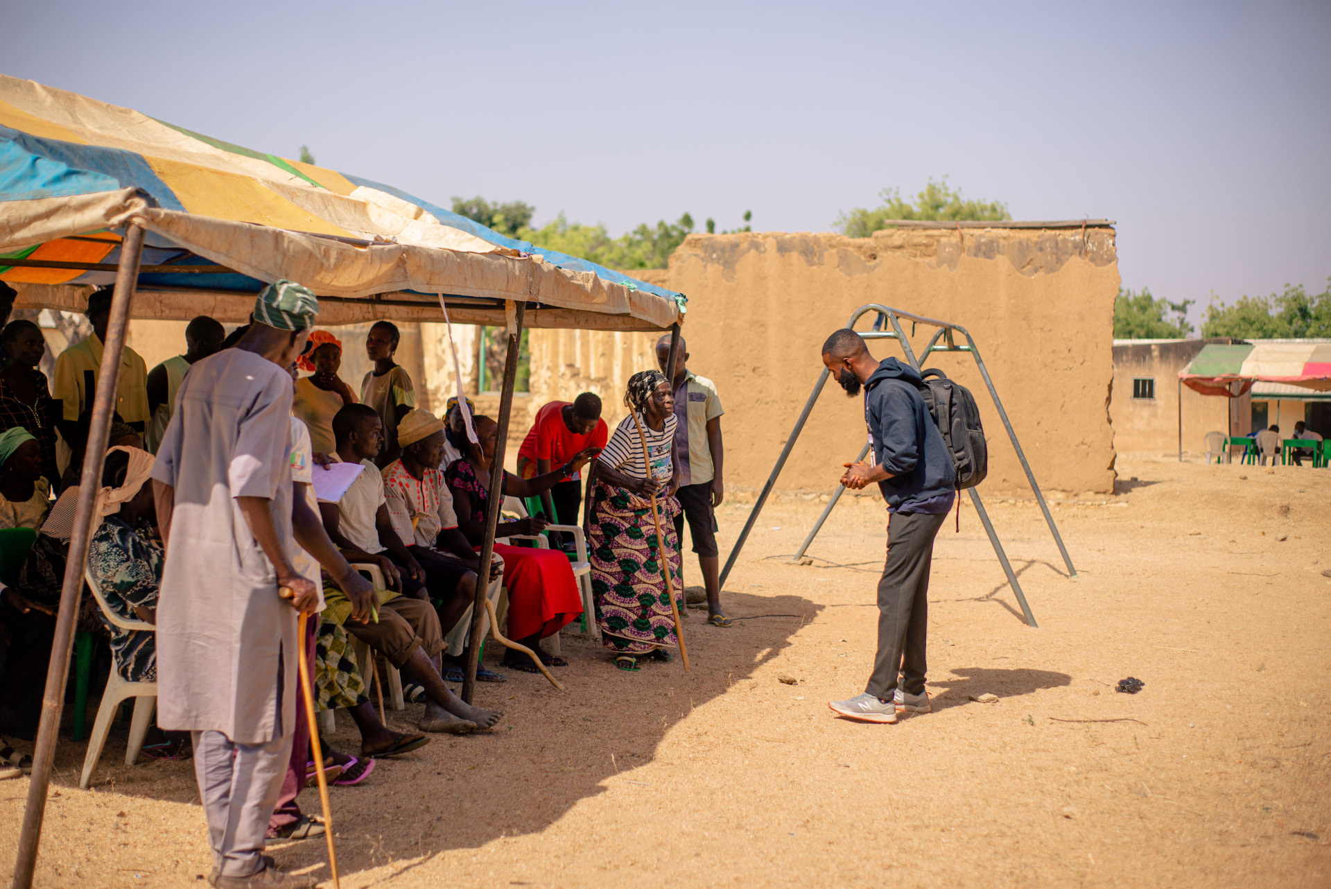 Foundation team member briefing patients seated under a canopy at a rural eye camp